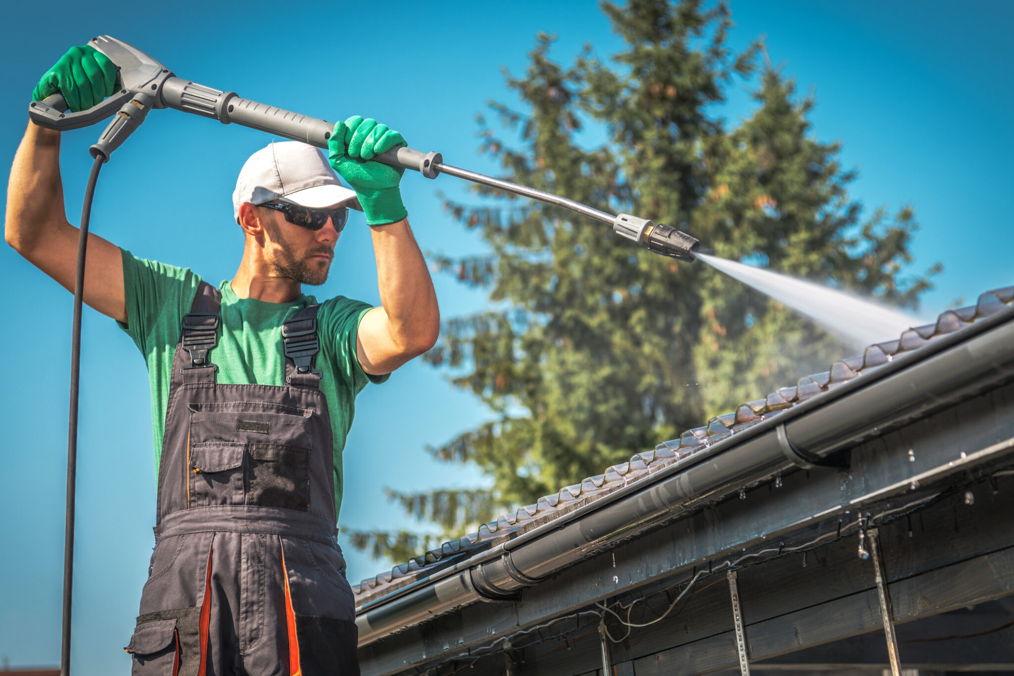 Worker cleaning the roof using pressure washer